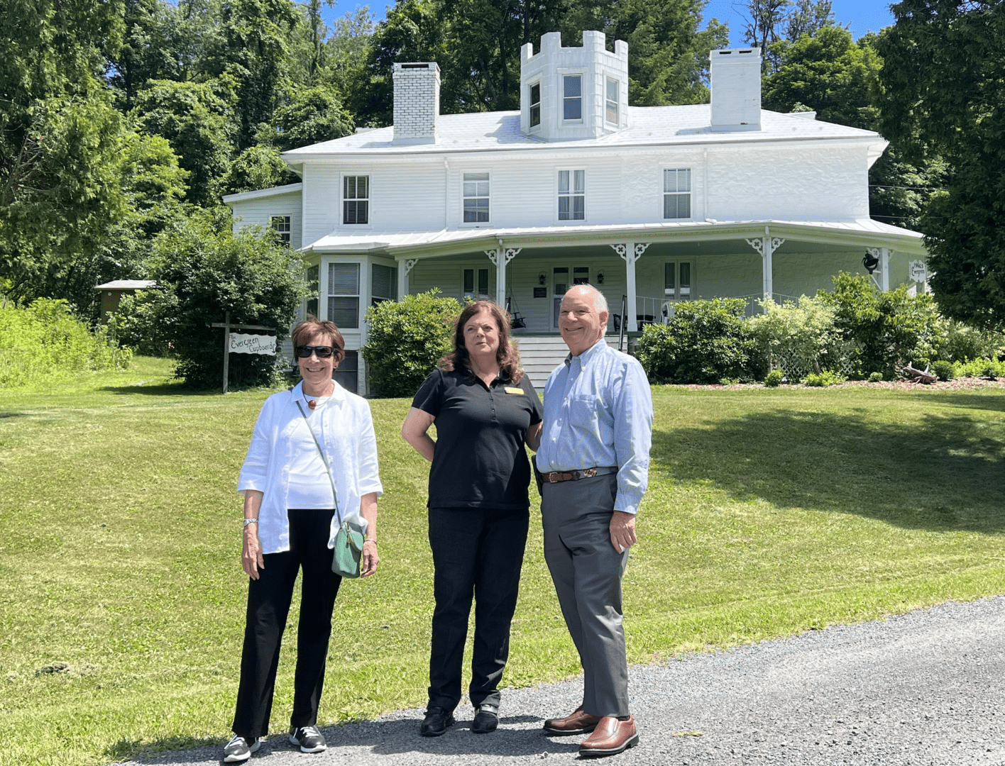 Three people standing in front of a white house.